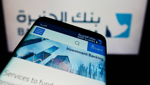 Stuttgart, Germany - 12-12-2021: Mobile phone with webpage of Saudi Arabian company Bank Aljazira (BAJ) on screen in front of business logo. Focus on top-left of phone display.