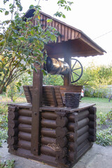 rural wooden well and black bucket of water
