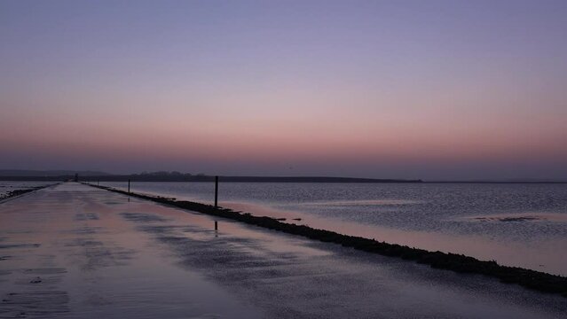 Sunset over sand on Lindisfarne holy island relaxing and meditation in nature. Northumberland seaside with sun going down over water in evening UK 4K