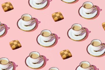 Coffee cups and cookies, creative pattern on pastel pink background.