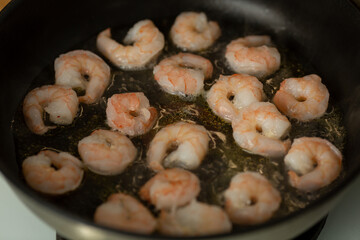Shrimp are fried in a heated frying pan in olive oil