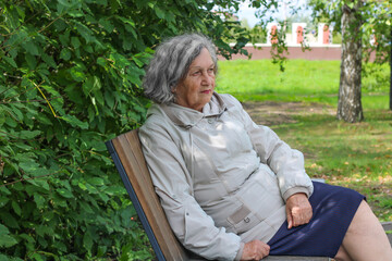 An elderly woman with gray hair is warmly dressed in cool weather. Retirement age