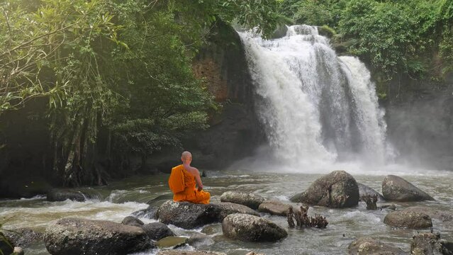 Buddha monk practice meditation at  waterfall in rainforest