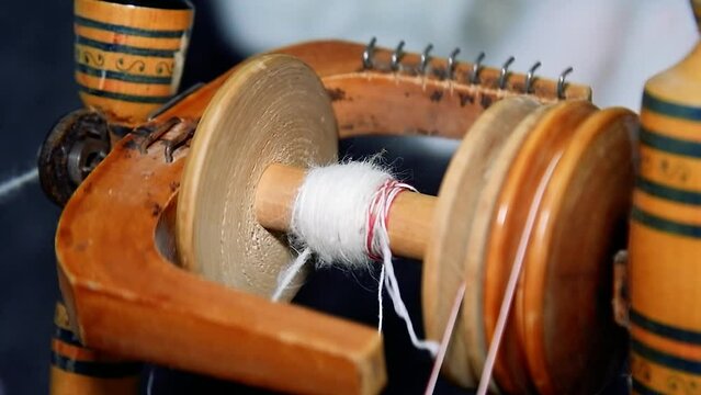 Action detail of hands working old fashioned wool spinning wheel