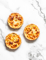Mini quiche with canned tuna and mozzarella on a light background, top view