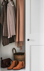 Women's autumn clothes on a hanger in the wardrobe - plaid jacket, vest, bag and chelsea boots