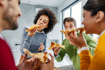 A multicultural businesspeople having pizza for lunch in the office for a lunch break.