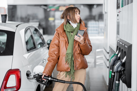 Woman refueling car with gasoline, using smartphone to pay. Concept of mobile technology for fast refueling without visiting the store