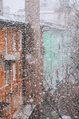 Abstract snowfall in the old town, snowflakes fall on the background of colored buldings