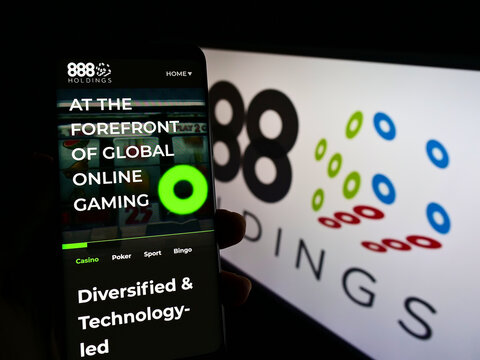 Stuttgart, Germany - 12-12-2021: Person holding smartphone with website of online gambling company 888 Holdings plc on screen in front of logo. Focus on center of phone display.