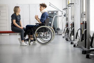 Rehabilitation specialist talking with a guy on wheelchair at rehabilitation center. Concept of mental health and recovery after injuries