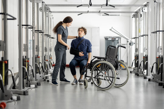 Rehabilitation specialist talking with a guy on wheelchair at rehabilitation center. Concept of mental health and recovery after injuries
