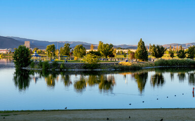 Fototapeta premium Sparks Marina Park during golden hour in late summer with birds in the water, a clear blue sky and mountains in the background.