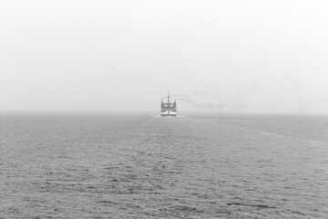 Foggy morning in the sea. Ship in black and white. 