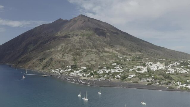 Stromboli Island from the sea with black sand from the volcano and boats
