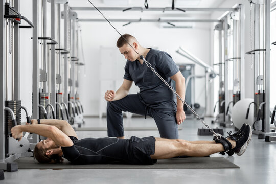 Man doing exercises on decompression simulators with the help of rehabilitation specialist. Concept of physical therapy for health and recovery. Idea of kinesiology in the treatment of back