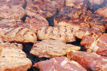 Pieces of meat are fried on the grill close-up.