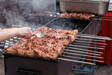 The cook checks the readiness of the kebab with a special large fork. Selective focus.
