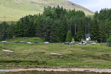 Autos und Wohmobile parken auf einem Parkplatz im Tal Glen Coe in den Schottischen Highlands,...