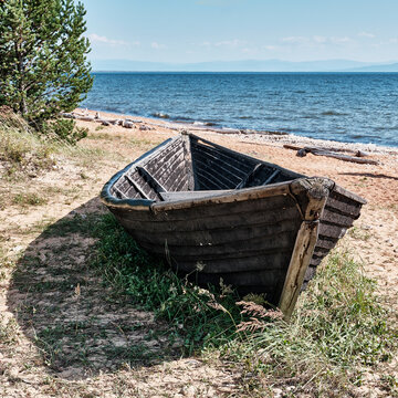 Old fishing wooden longboat on shore of Kultuk Bay. Lake Baikal, Zabaikalsky National Park, Russia.