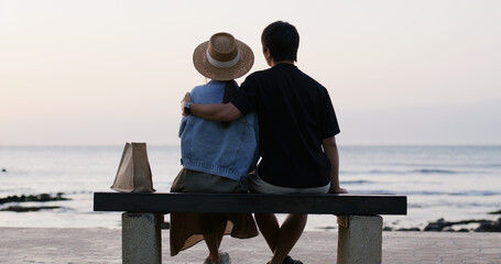 Couple sit on the bench and look at the sea