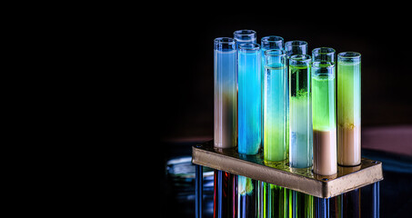 Colorful shot drinks in glass tubes. Dark background, atmospheric bar image. Laboratory glassware with alcohol cocktails on chemical party