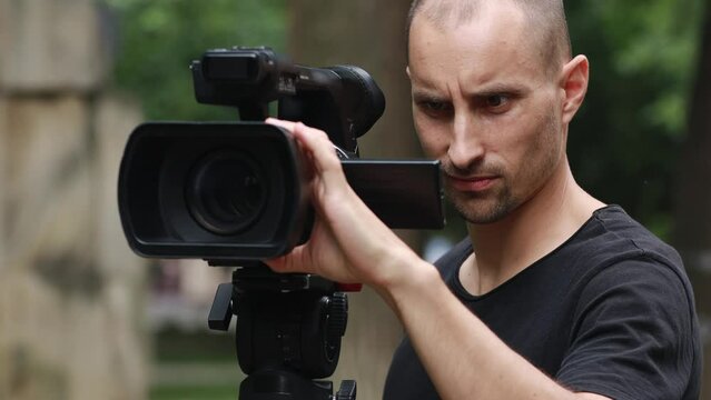 Man Videographer With Professional Camcorder Shoots Video Outdoors