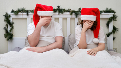 Sad man and woman on a bed decorated for Christmas and New Year, family couple in home bedroom