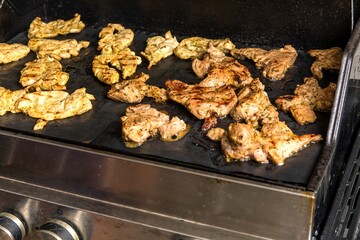 Chicken meats being stirred on non stick grill teflon mat. Grilled meat.