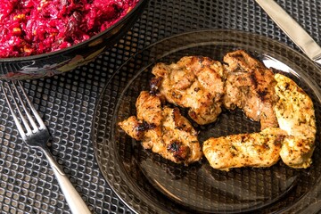 Glass plate with grilled meat. Beet-root salad. Grilled turkey meat.