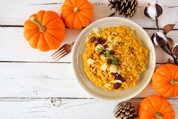 Autumn pumpkin risotto with cranberries and parmesan cheese. Above view table scene on a white wood...