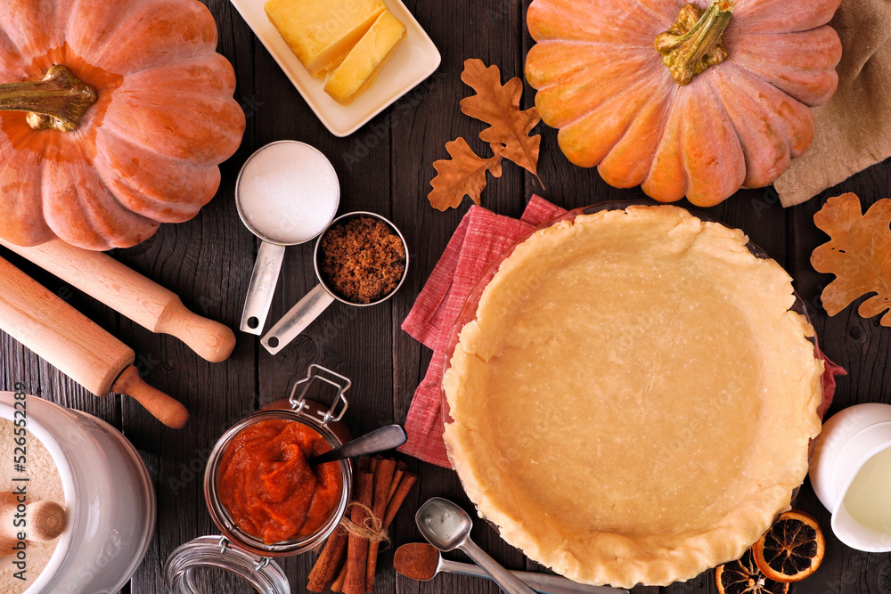Poster autumn baking table scene with pumpkin pie ingredients. overhead view on a dark wood background.
