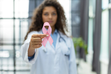 Doctor holding pink breast cancer awareness ribbon. Medicine and healthcare concept, women's health - obrazy, fototapety, plakaty