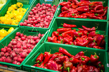 Plastic boxes with vegetables of the supermarket, sweet pepper and radish on the counter