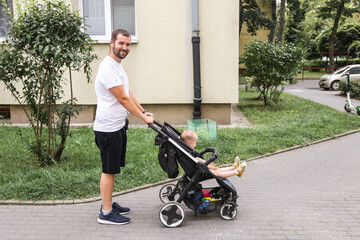 young dad walking with a baby in a stroller