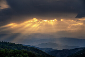 Beautiful summer mountain landscape, clouds and sun rays at bright sunset