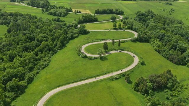 Aerial drone view of winding road between green fields