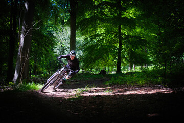 Mountain biker cornering hard in a forest pool of light