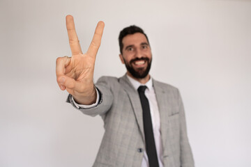 Portrait of outgoing man with beard. Male in suit gesturing, showing victory sign. Portrait, emotion concept