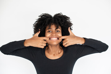 Portrait of funny African American woman teasing showing teeth. Young female model wearing black dress looking at camera and playing fool. Fun and humor concept