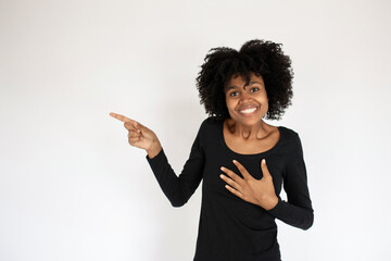 Cheerful African American woman pointing and laughing. Portrait of young female model wearing black dress showing something and smiling at camera. Mockery concept