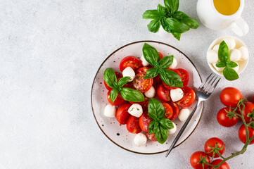 Italian caprese salad with sliced tomatoes, mozzarella, basil, olive oil on a light background. Top view. Italian food. Healthy salad. Summer food