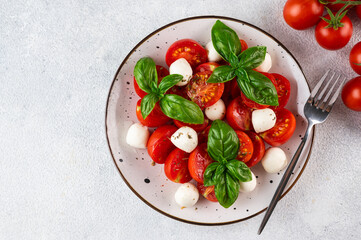 Italian caprese salad with sliced tomatoes, mozzarella, basil, olive oil on a light background. Top view. Italian food. Healthy salad. Summer food