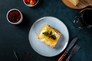 Piece of tasty hot lasagna on dark background. Traditional italian lasagna. Italian food. Close up lasagna. Bolognese sauce. Bechamel sauce. Still life of food. Homemade meat lasagna.