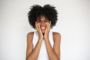 Portrait of happy young woman holding head in hands. Young African American woman wearing white top looking at camera. Admiration and surprise concept