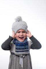 Portrait of a little girl in a hat and scarf on a white background.