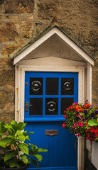 Colorful front door in seaside town with flower basket and green plant