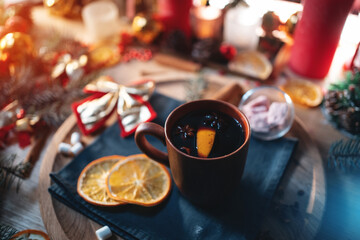 Obraz na płótnie Canvas mulled red wine gluhwine in cup with orange, christmas decor table with candles