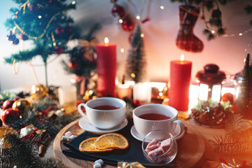 two cups of black or berry red hot english christmas tea with decor and candle - obrazy, fototapety, plakaty