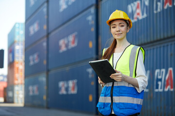 factory worker or engineer holding tablet for work in containers warehouse storage